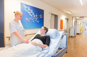 Patient:in im Bett mit Pfleger_in