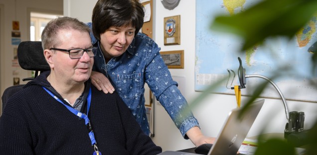 Anja und Tomas Gerlach schauen in einen Monitor, sie lächeln