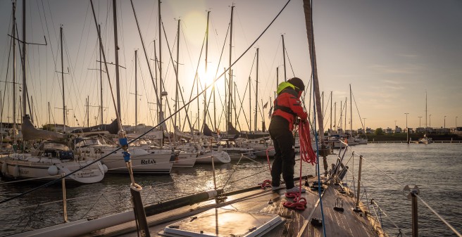 Segelrebellen, Abendstimmung, das Boot wird vertäut, eine Frau steht am Bug