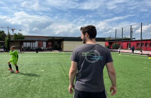 Mann mit T-Shirt von Hinten auf einem Fußballplatz